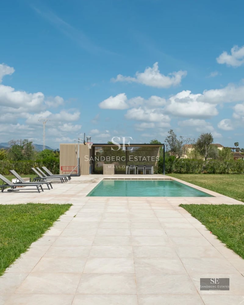 Spacious balcony with sea view, modern outdoor furniture, glass railing, wood flooring, and lush vegetation.