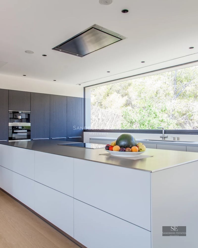 Bright living room with large windows, outdoor pool, light wood floors, and minimalist design. Beige sofa and stone details.