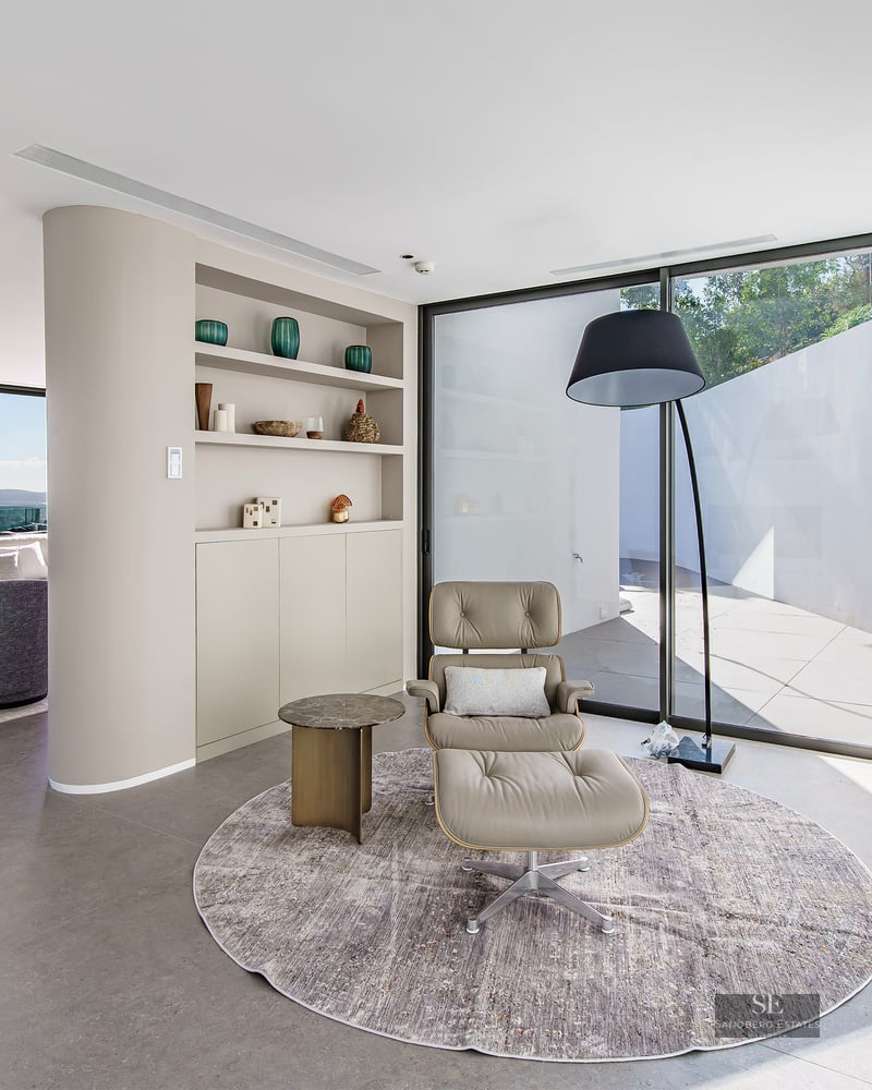 Minimalist reading nook with leather lounge chair and floor-to-ceiling windows overlooking the city.
