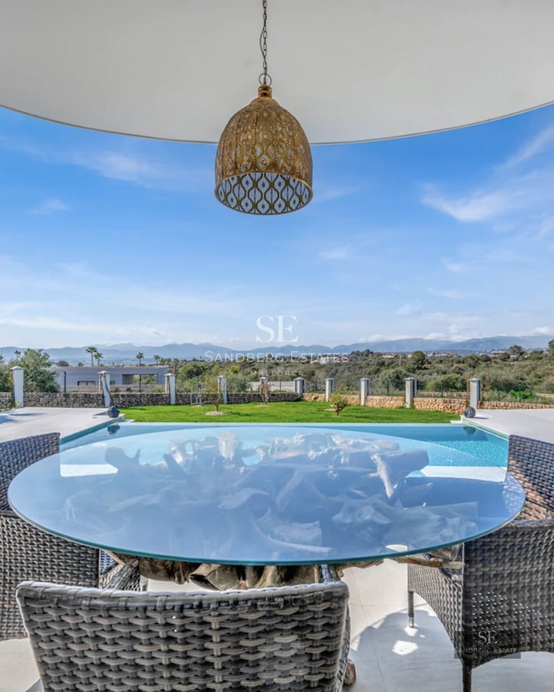 Spacious living room with large windows, pool reflecting the light. Modern design with minimalist furniture and wood accents.