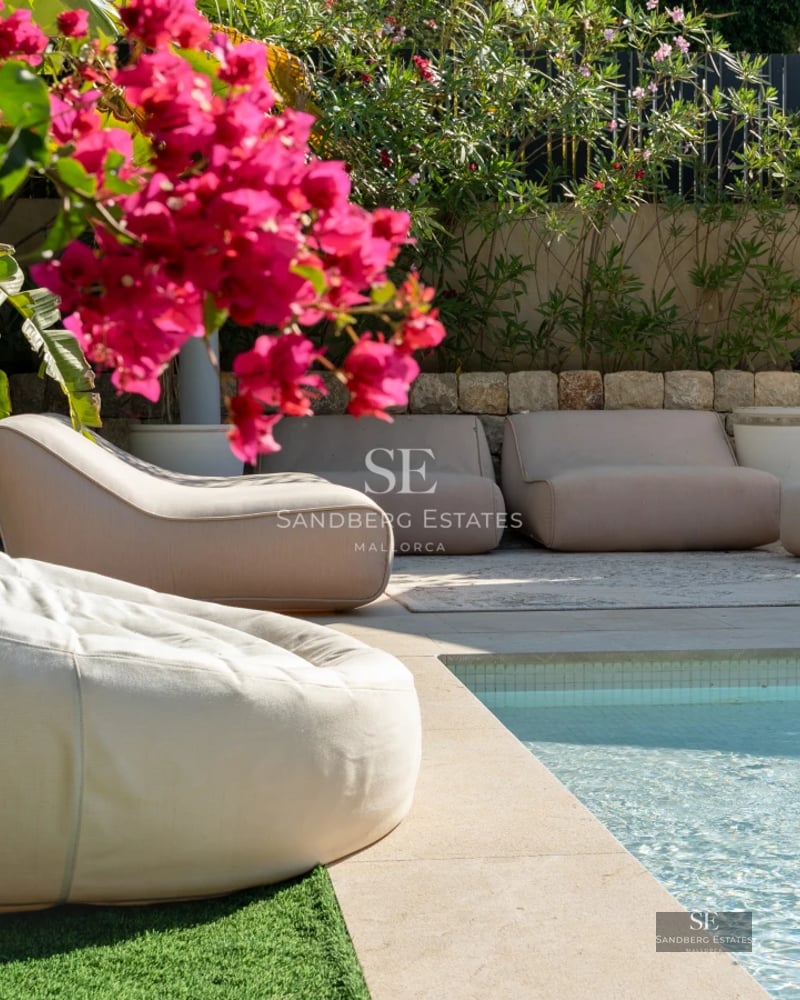 Spacious living room with panoramic views. Modern sofa, elegant rug, warm lighting and large windows overlooking the terrace and pool.