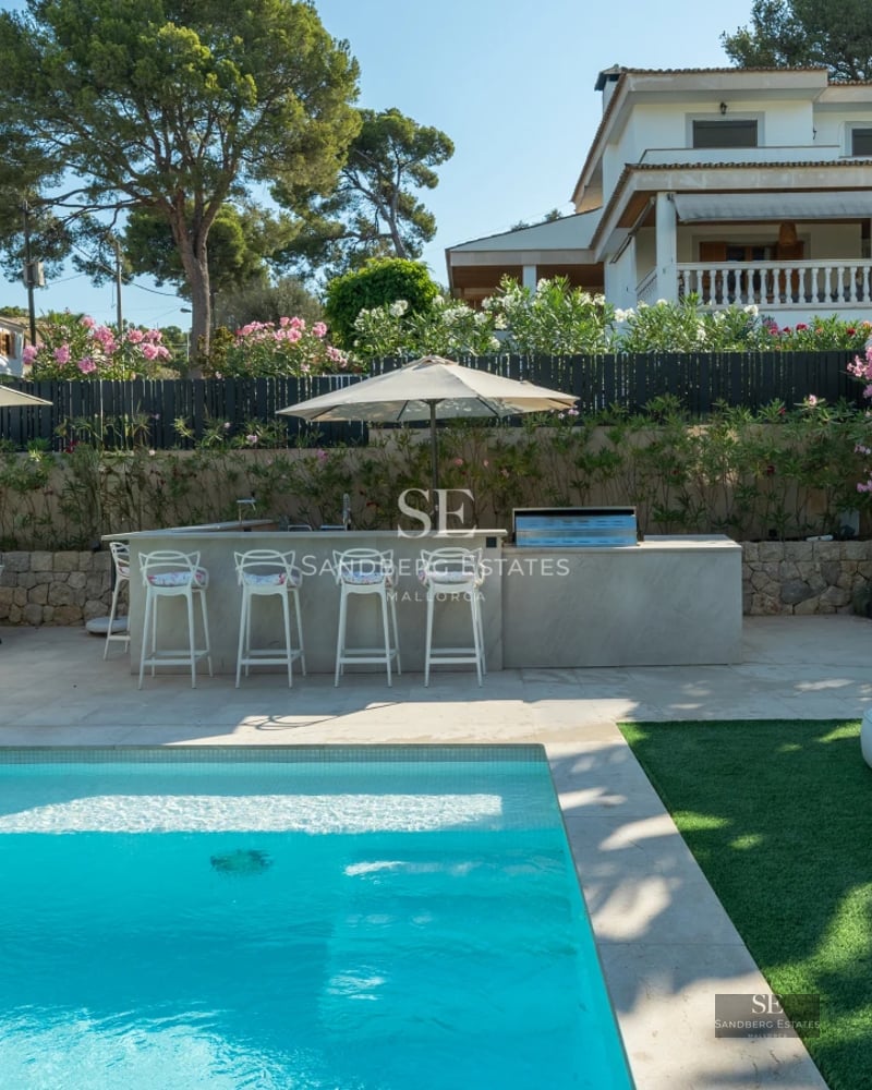 Exterior view of a modern villa with an infinity pool, spacious terraces, and lush garden. Minimalist architecture with large windows.
