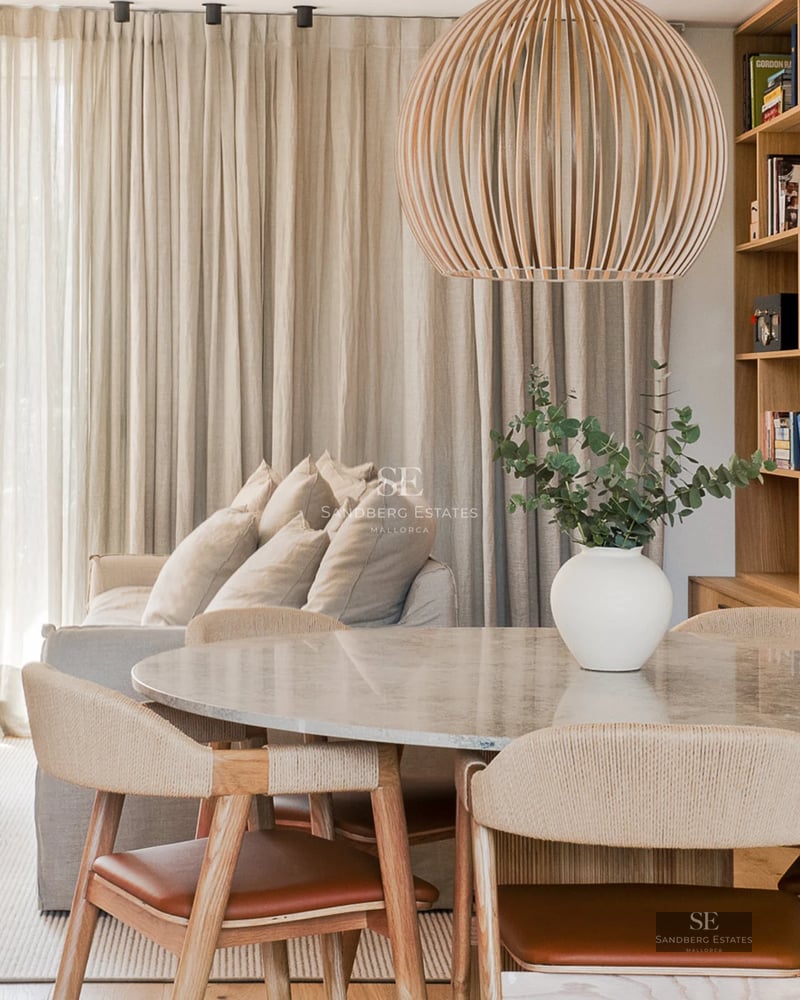 Modern penthouse featuring a glass-enclosed balcony, sea views, and a minimalist design. Bright interior with wood floors and designer furniture.