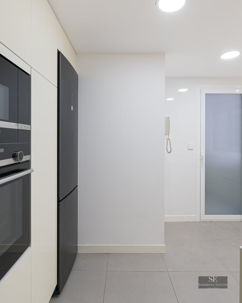 Modern white kitchen with built-in black Siemens oven and microwave, grey floor tiles, and recessed lighting.