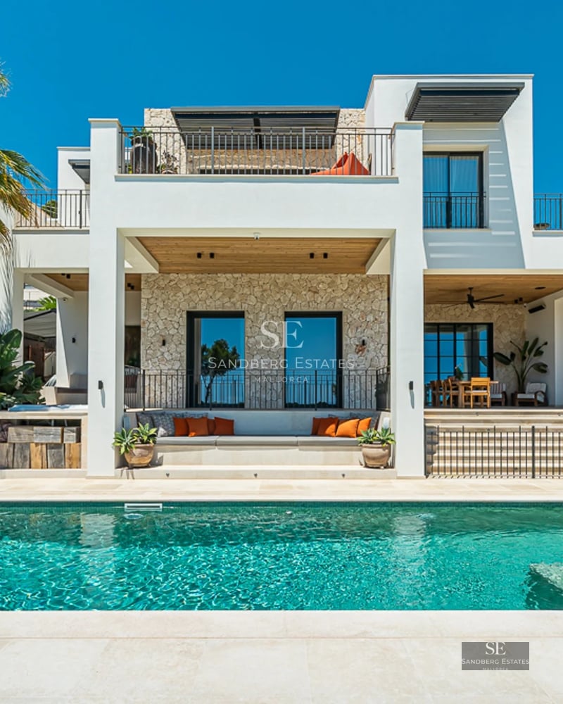 Vue extérieure d'une villa moderne avec piscine à débordement, jardin paysager et grandes baies vitrées. Design architectural minimaliste.