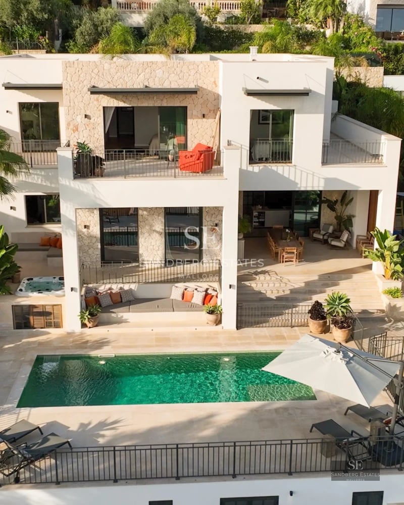 Balcon moderne avec rambarde en verre, vue sur mer et mobilier design. Éclairage chaleureux et finitions luxueuses.