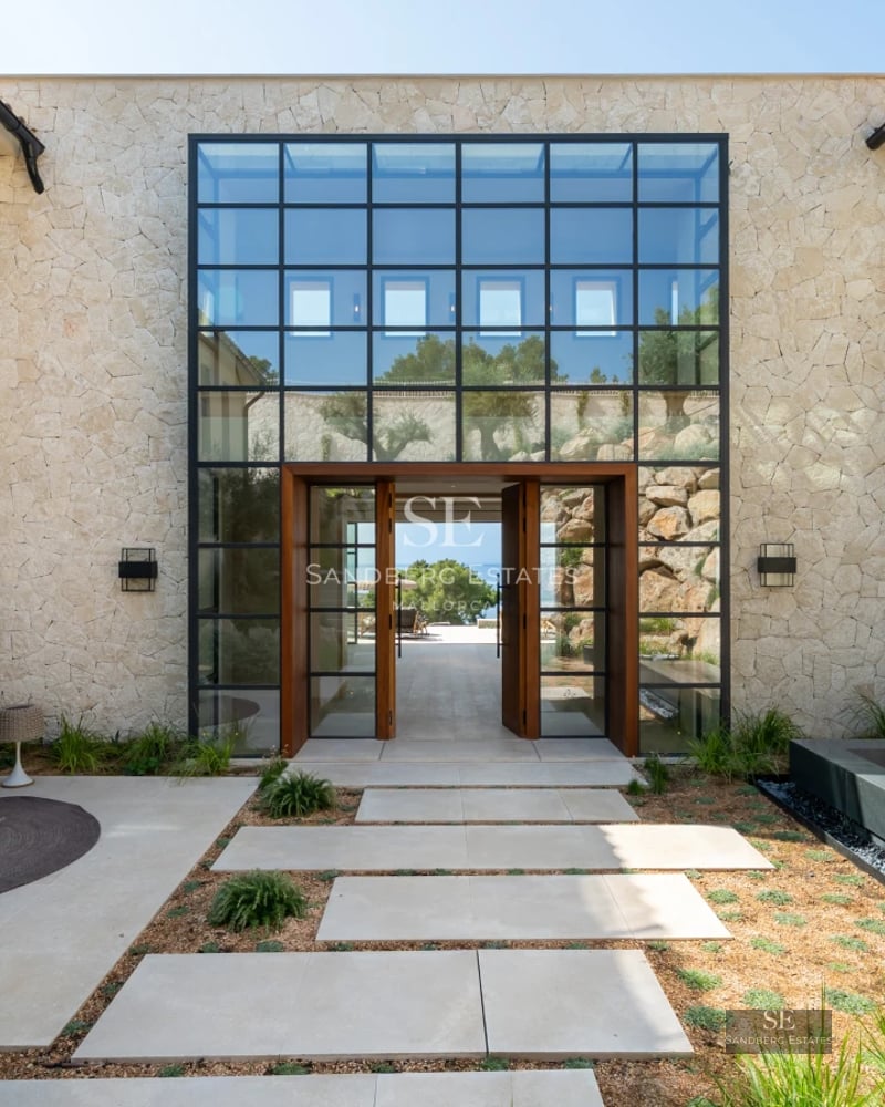 Spacious living room featuring floor-to-ceiling windows, natural light, wood floors, light-colored sofas, and city views. Modern and elegant design.