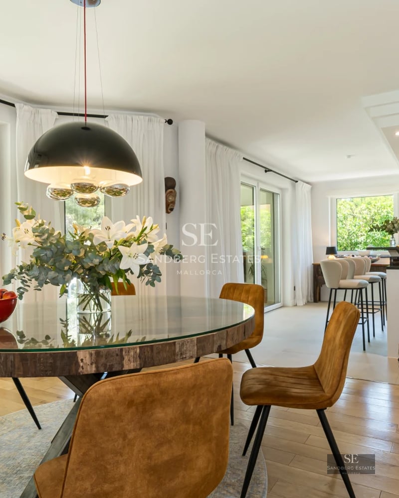 Spacious living room with windows overlooking the garden and pool. Modern design, light wood floors and minimalist furniture.