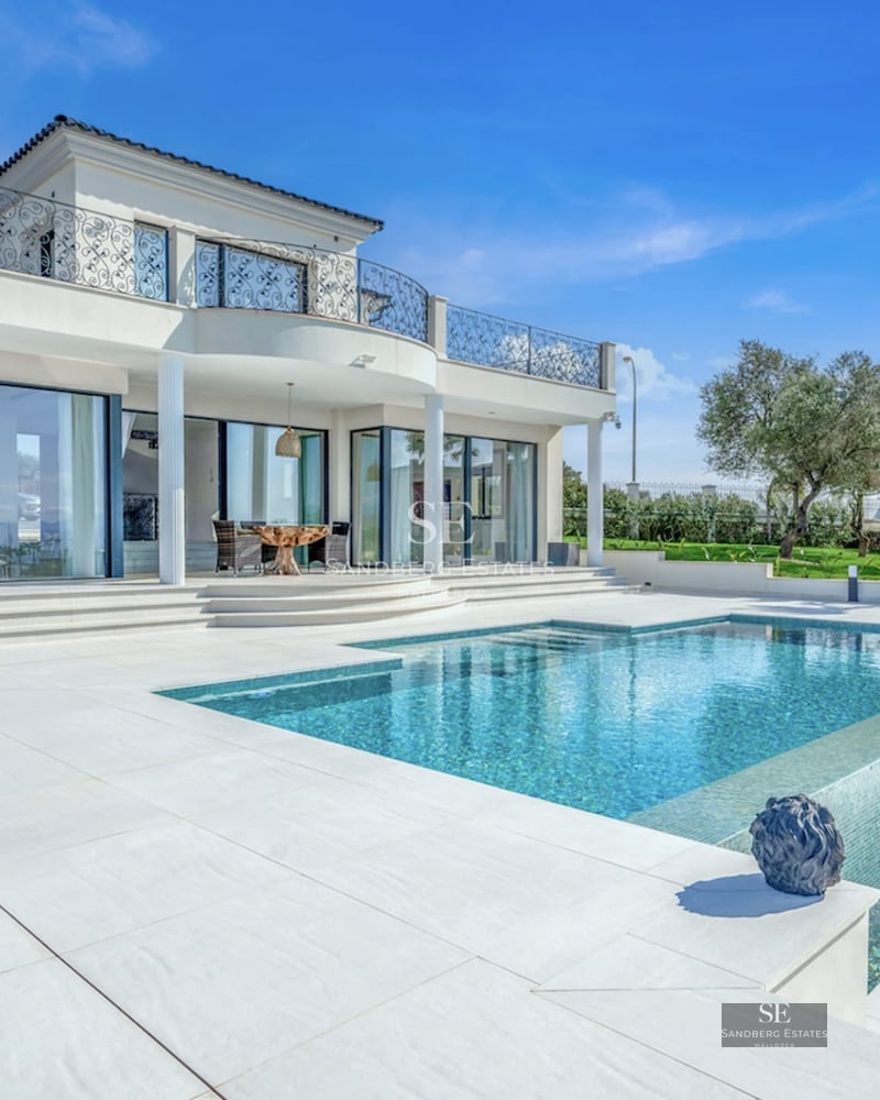Spacious living room with pool view. Modern design, natural light, neutral colors. Light wood floors and elegant furniture.