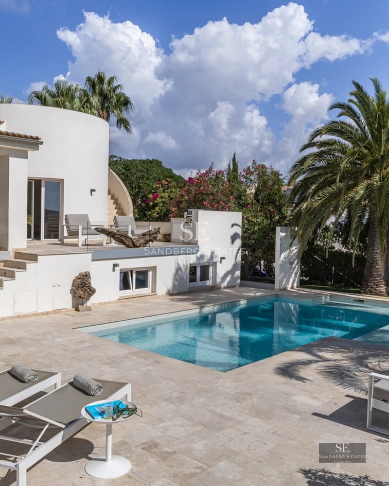 Exterior view of a modern house with an infinity pool, lush garden, and spacious terraces. Minimalist architecture with large windows.