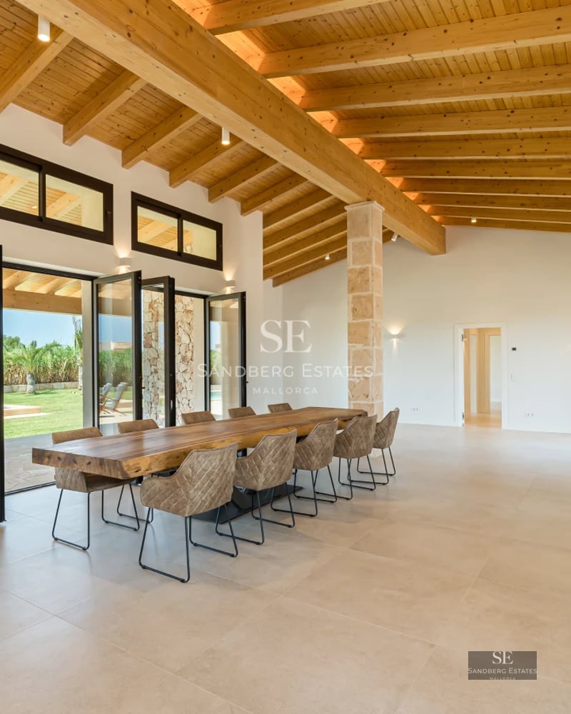 View of living room with beige sofa, wood coffee table, light rug and large window with sea view. Modern and bright design.
