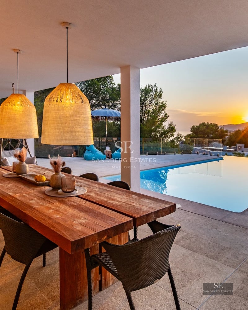 Exterior view of a modern villa with infinity pool, terrace, lush garden, and large windows providing natural light.
