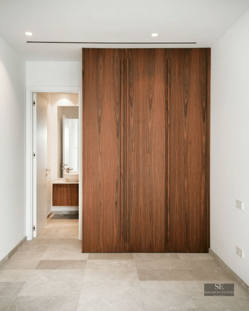 Large floor-to-ceiling dark wood closet next to a white doorway leading to a modern bathroom.
