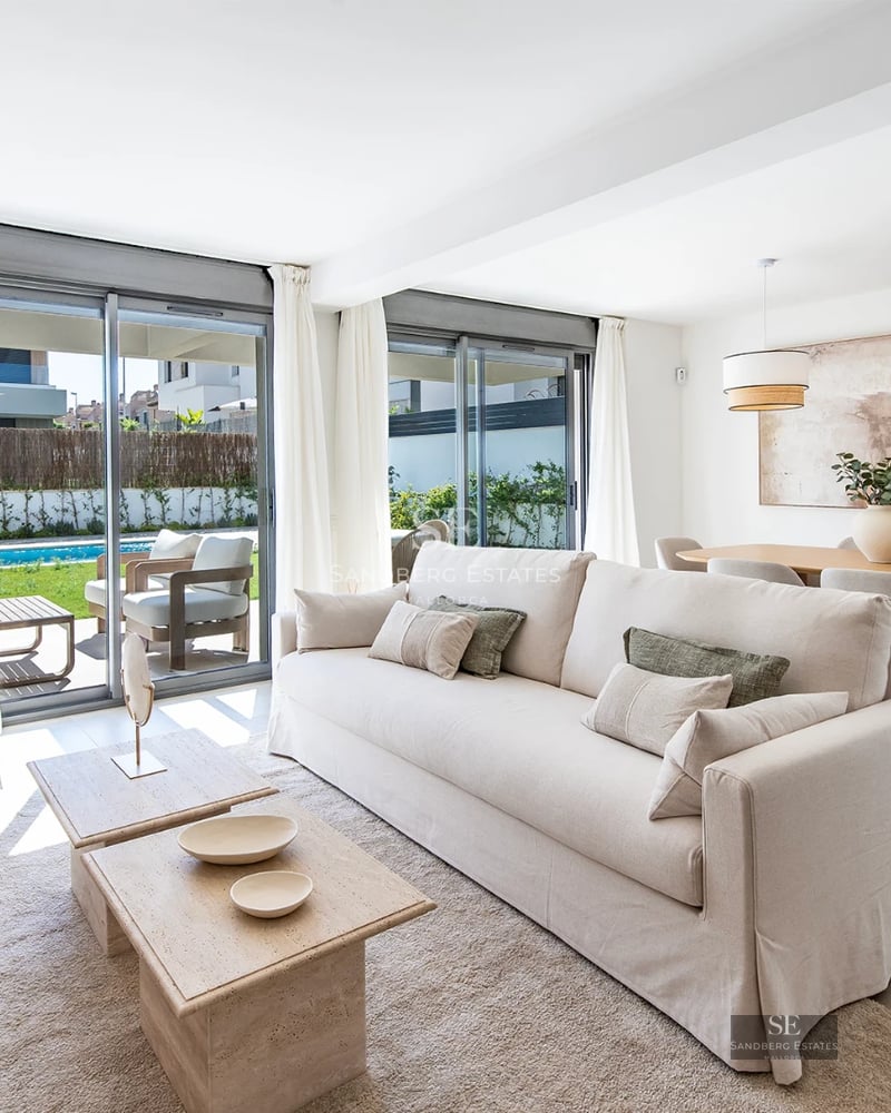 Large, reflective pool surrounded by minimalist terrace. Modern design, natural light, immaculate lawn and bright blue sky.