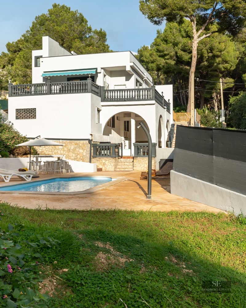 Villa blanche avec piscine privée, terrasse, pelouse et entourée d'une forêt de pins dense.