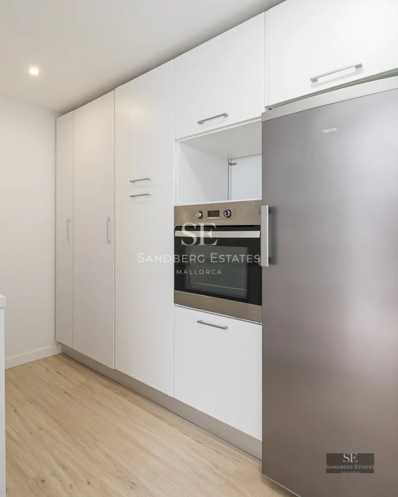 Spacious balcony with sea view, wood flooring, glass railing, modern furniture. Natural lighting and minimalist design.