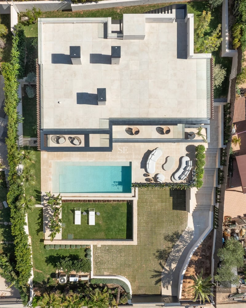 Exterior view of a modern villa with infinity pool, lush garden, and spacious terraces. Contemporary architecture.