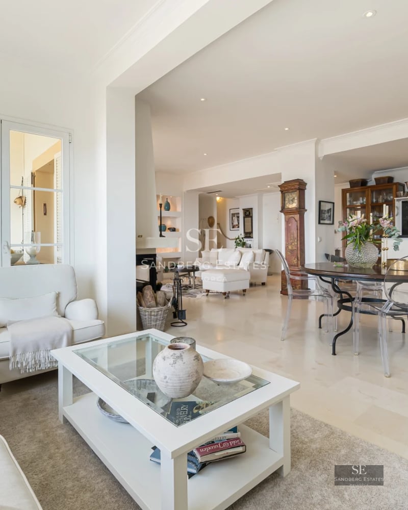 Spacious balcony overlooking the sea. Modern outdoor furniture. Glass railing. Warm lighting. Relaxing area. Sun loungers.