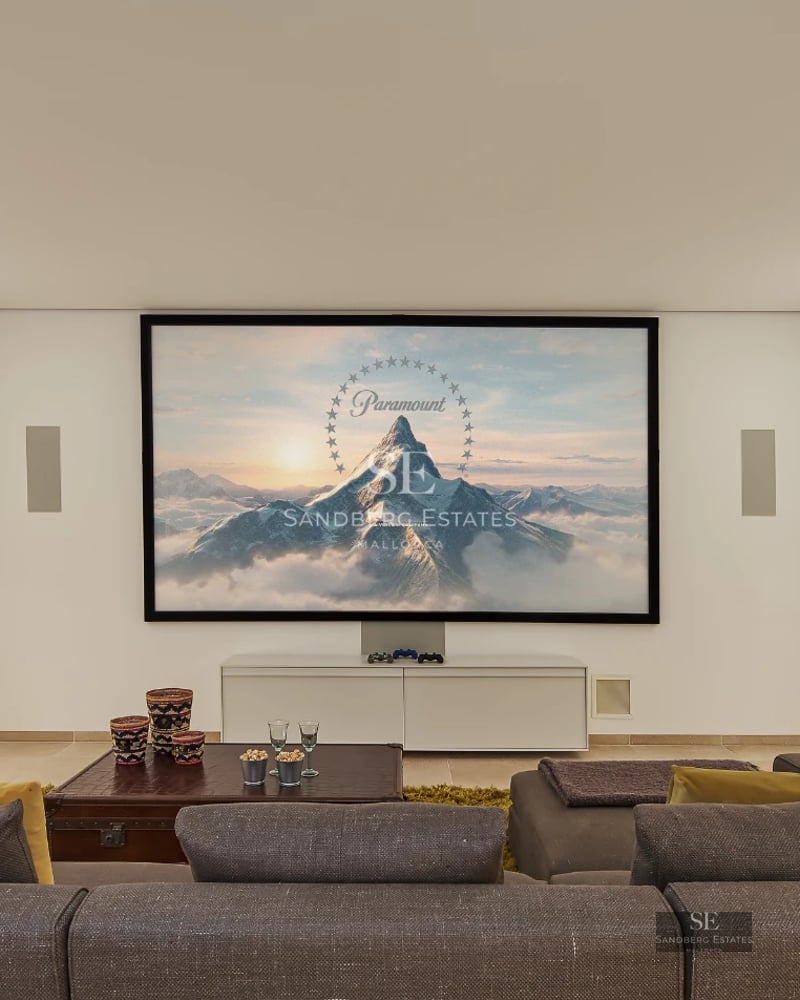 Spacious living room with fireplace, panoramic windows, and outdoor views. Modern design with wood floors and elegant furniture. Abundant natural light.