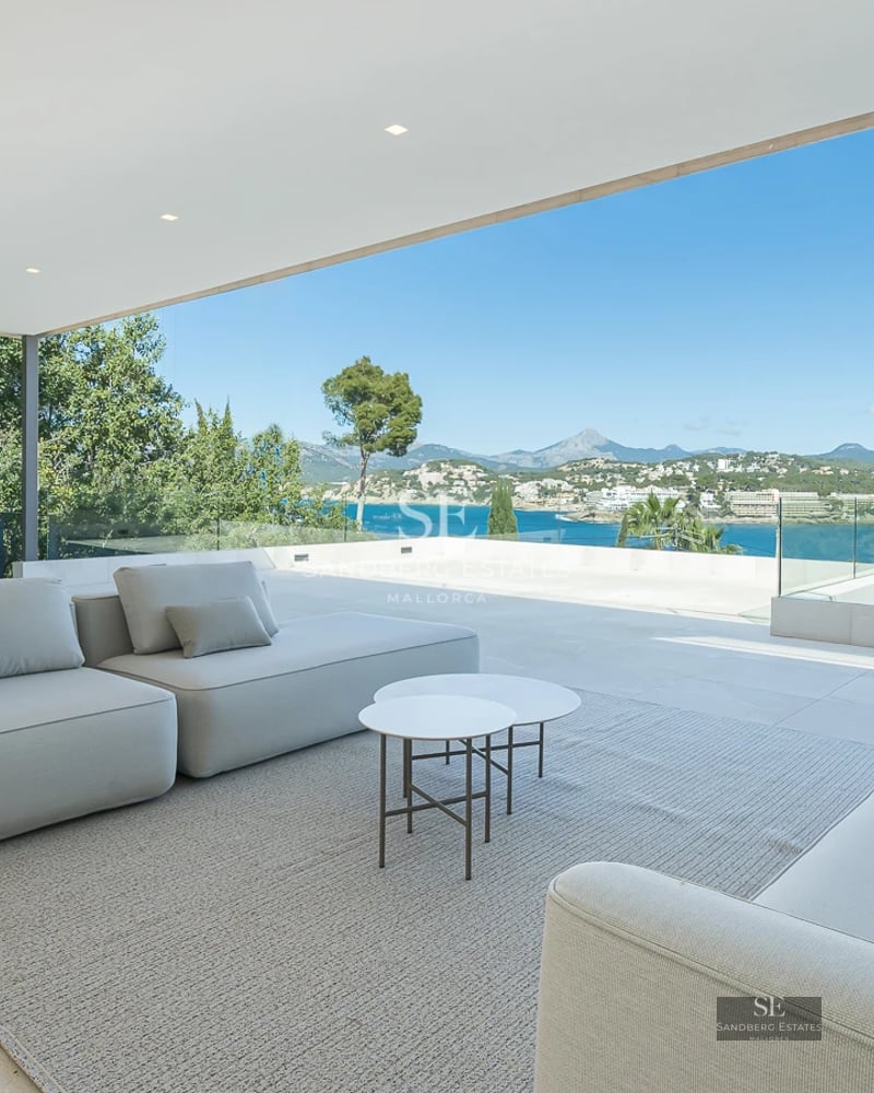 Bright living room opening to a balcony with sea view. Modern design, wood floors, minimalist decor and abundant natural light.