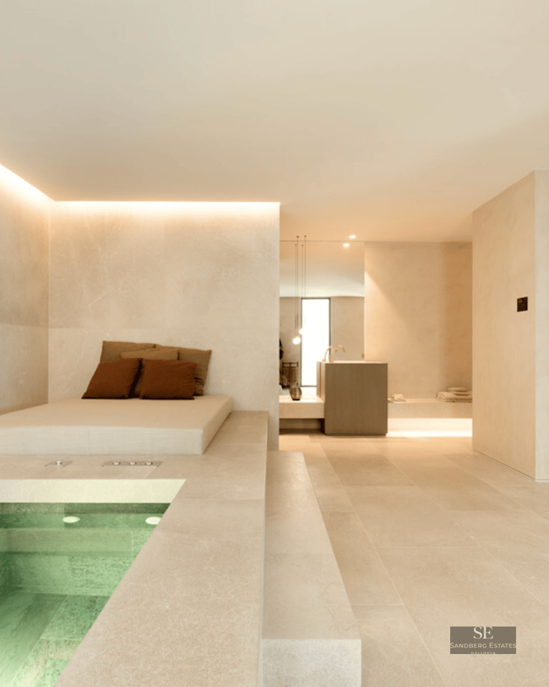 Modern indoor spa featuring a small square pool, a lounging daybed, and a glass-walled wooden sauna.