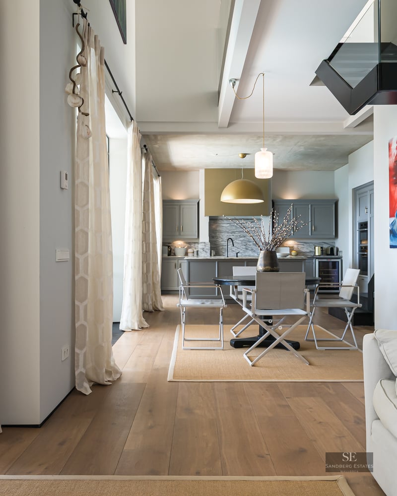 Bright open-plan living and dining room with wood floors, leading to an outdoor terrace and swimming pool.