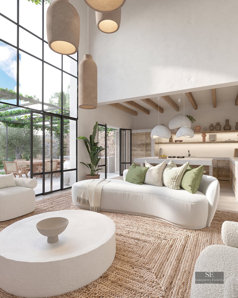 Spacious white living room with curved sofas, jute rug, and floor-to-ceiling windows overlooking a lush terrace.