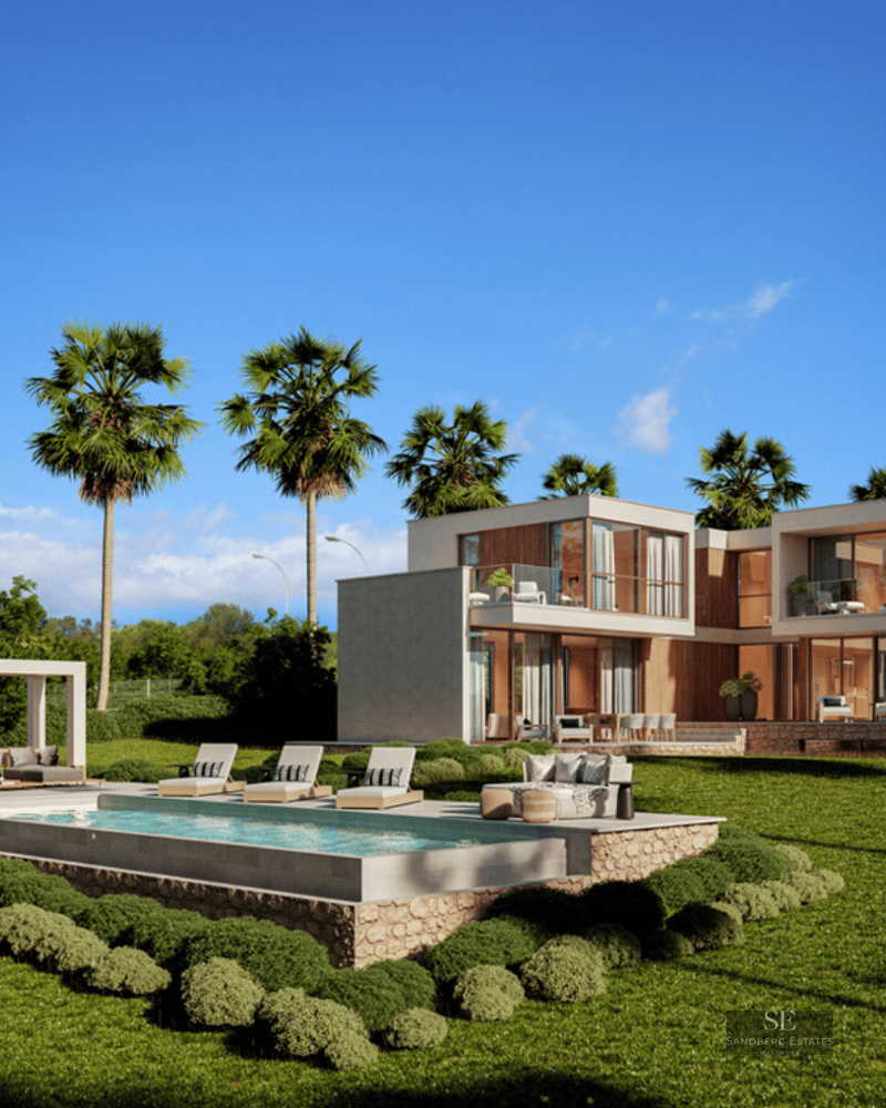 Modern two-story villa with a large swimming pool, sun loungers, and palm trees on a lush green lawn under a clear blue sky.