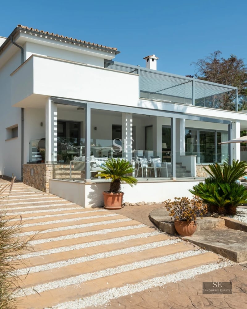 Exterior of a modern villa featuring an infinity pool, spacious terraces, and lush garden. Minimalist architecture, panoramic windows, and landscaping.