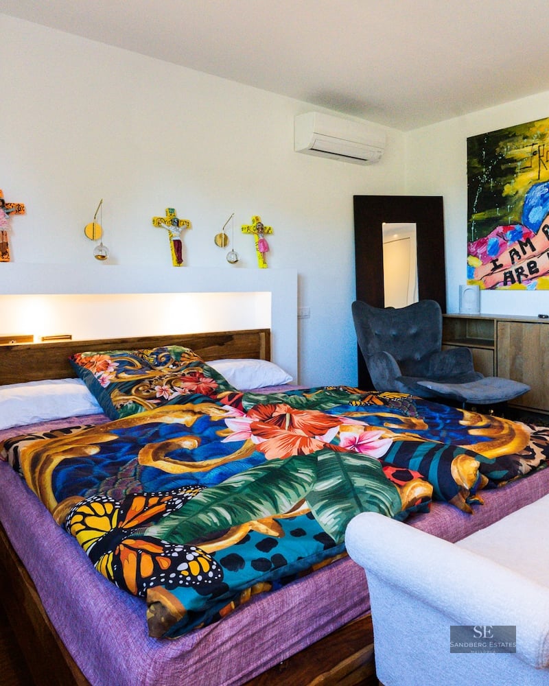 Bright bedroom featuring a bed with colorful floral bedding, large modern artwork, and warm recessed lighting.