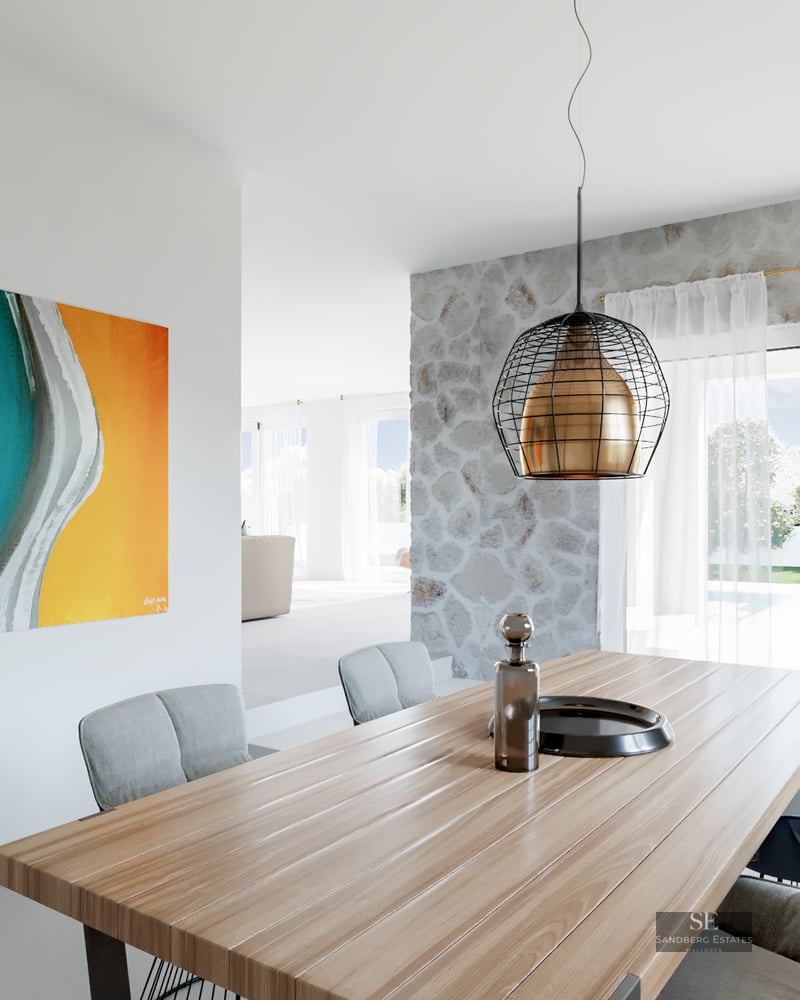 Modern dining area with wood table, designer lamp, stone wall, and vibrant abstract art overlooking a bright terrace.