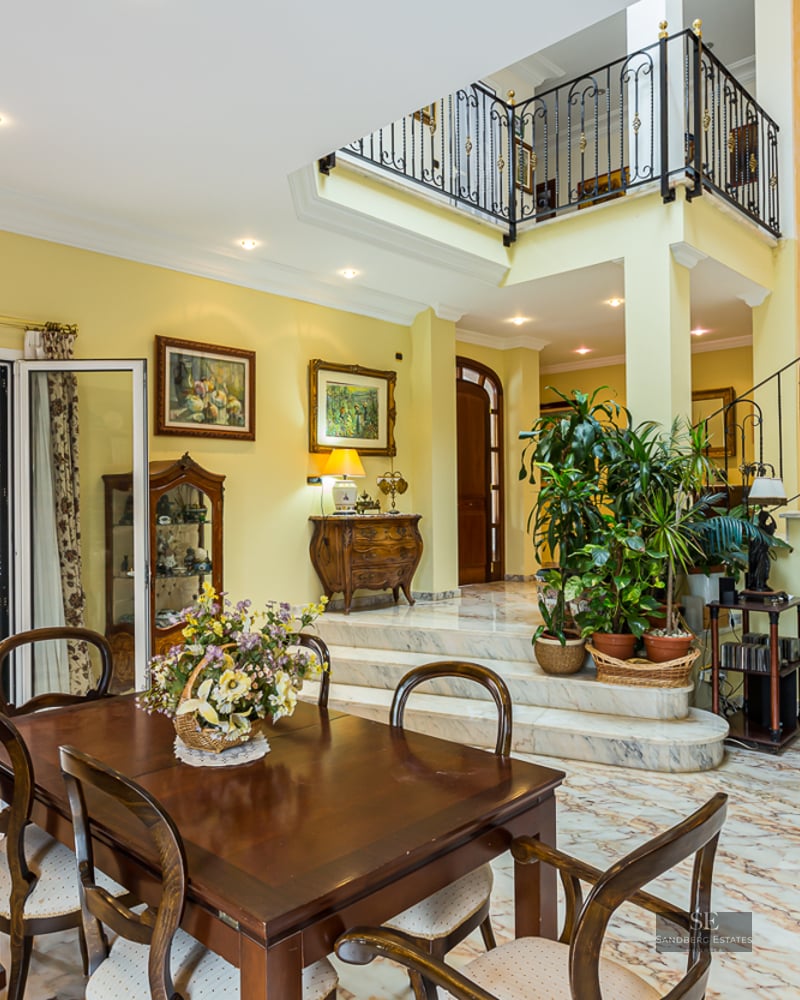 Grand dining room with marble floors, a wrought-iron staircase, and access to a terrace.