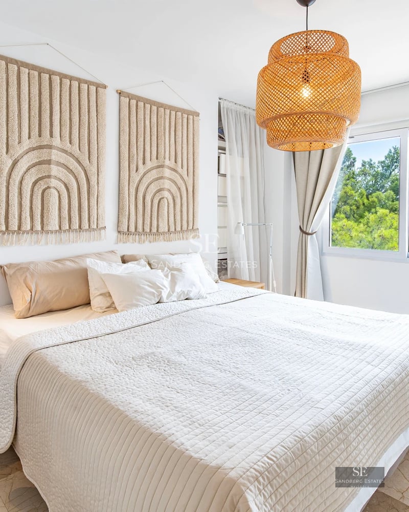Exterior of a modern villa featuring an infinity pool, lush garden, and minimalist facade with light stone and large glass windows.