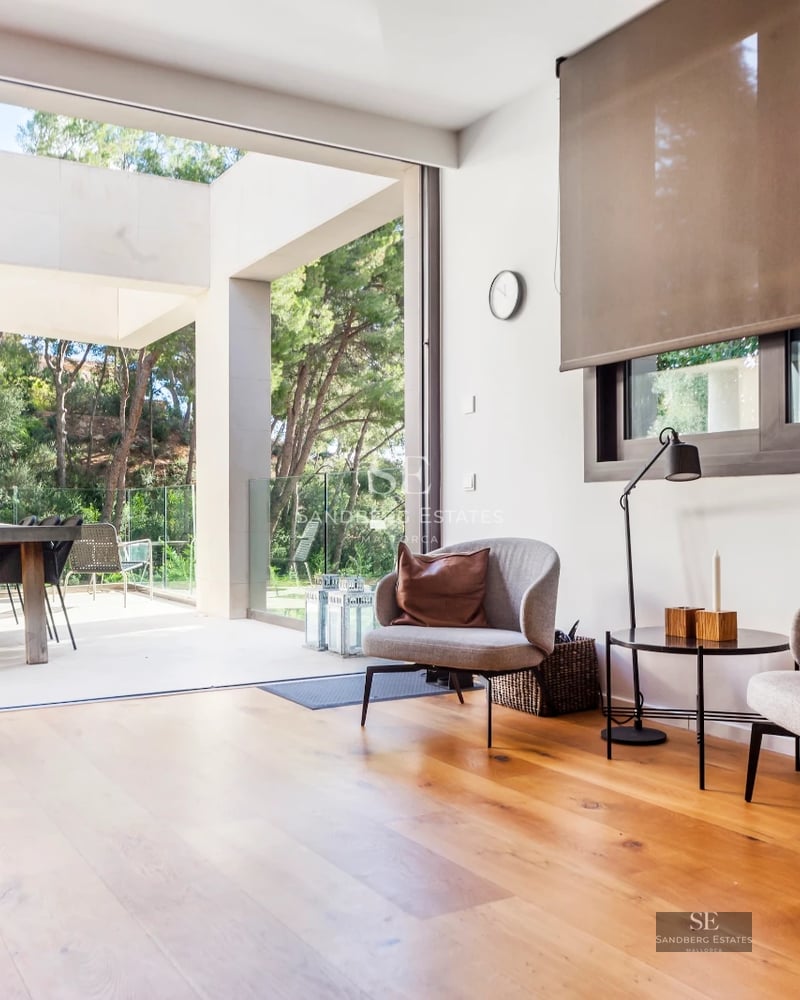 Exterior view of a modern villa featuring an infinity pool, lush garden, and spacious terraces. Contemporary architecture and manicured landscaping.