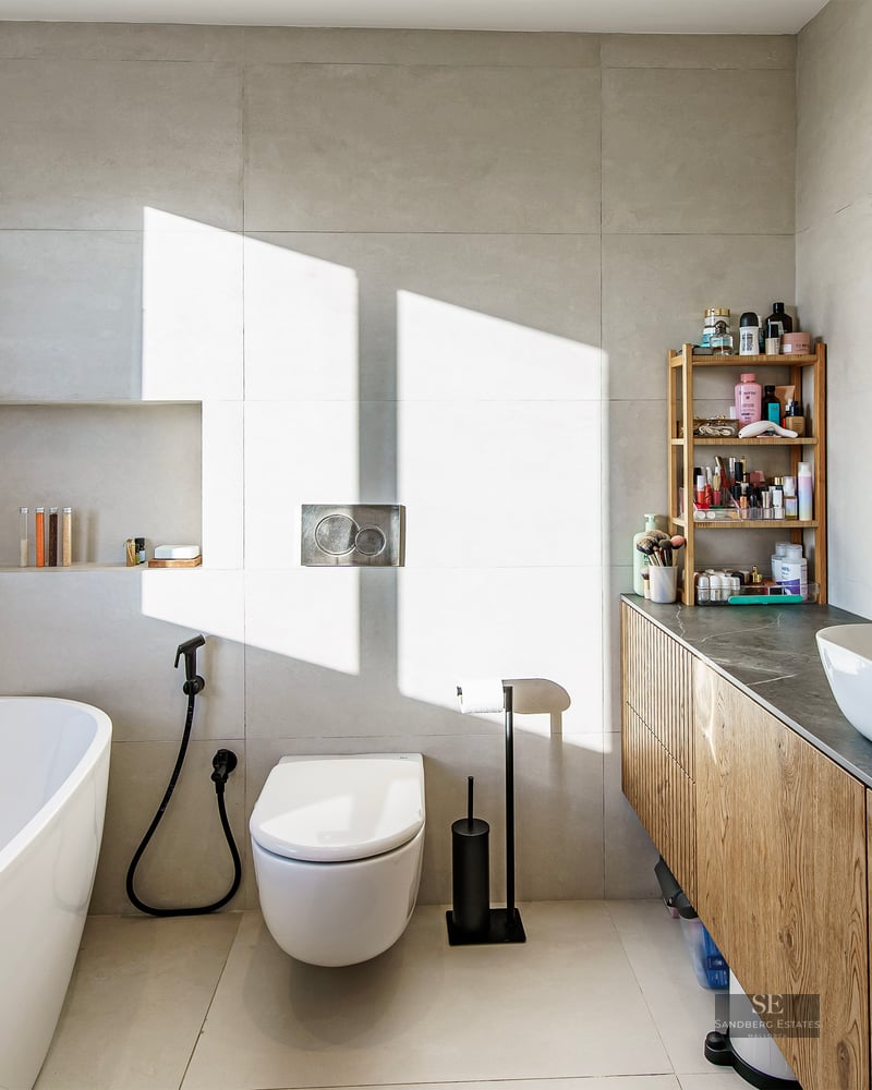 Bright modern bathroom featuring a white freestanding tub, wood vanity with vessel sink, and matte black fixtures.