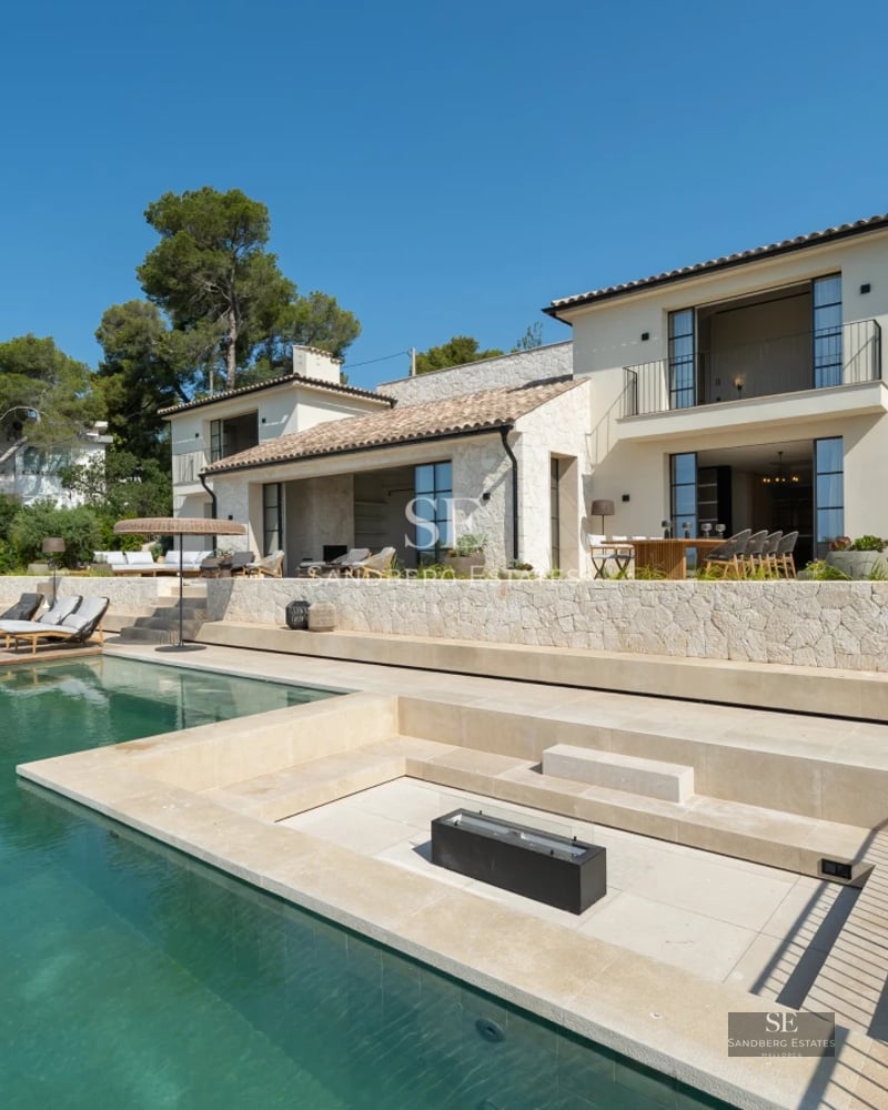 Pool view with sun loungers and lush greenery. Modern architecture with large glass windows. Natural light and relaxing atmosphere.