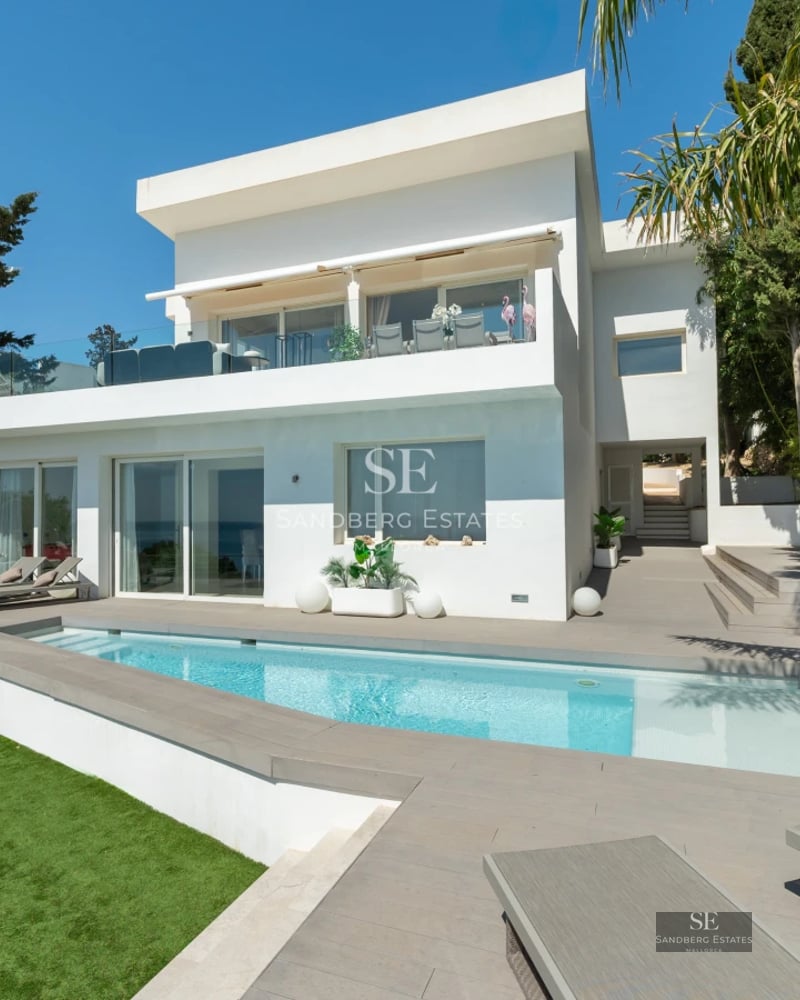 Spacious balcony with sea views, modern furniture, glass railing, and tiled flooring. Minimalist and bright design.