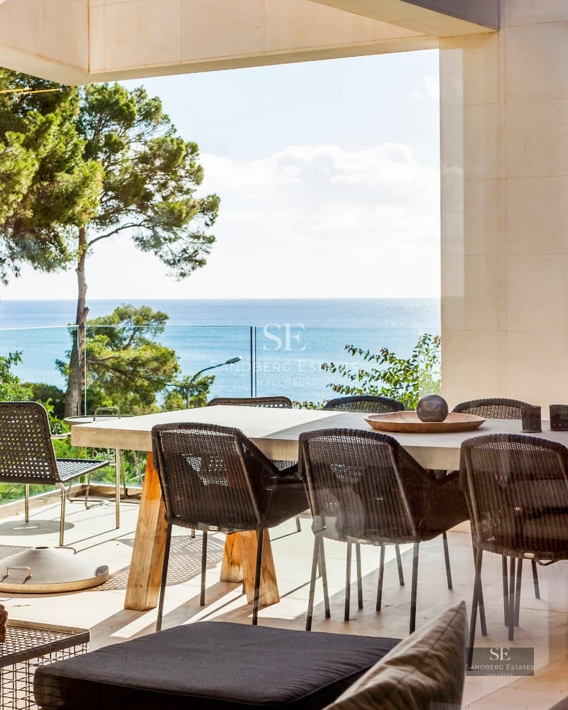 Spacious, bright living room with large windows overlooking a shimmering pool. Modern design with wood floors and elegant furnishings.