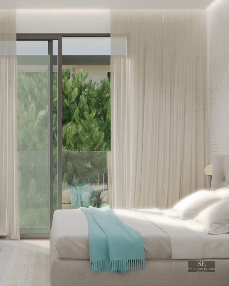 Bright bedroom with a tufted headboard, geometric textured wall, armchair, and glass doors opening to green foliage.