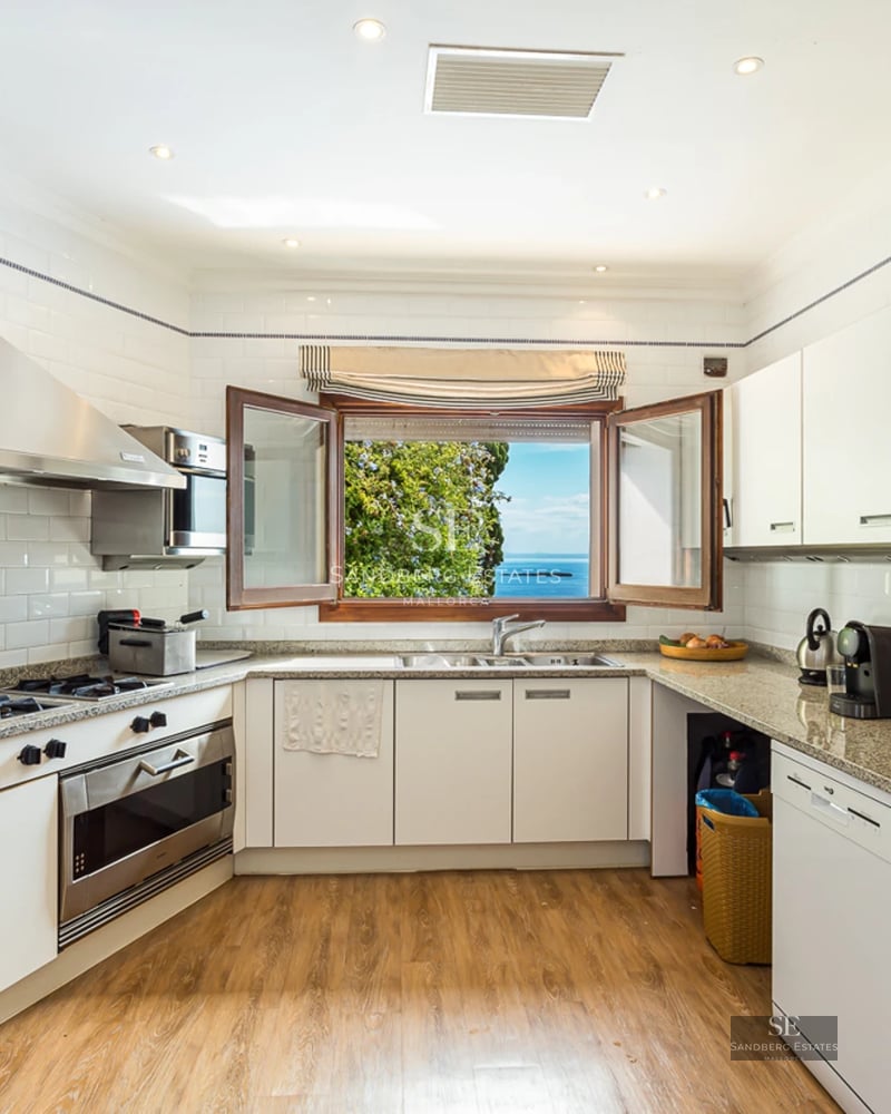 Extérieur d'une villa moderne avec piscine à débordement, grandes terrasses, design minimaliste et vues panoramiques. Façade blanche et végétation luxuriante.