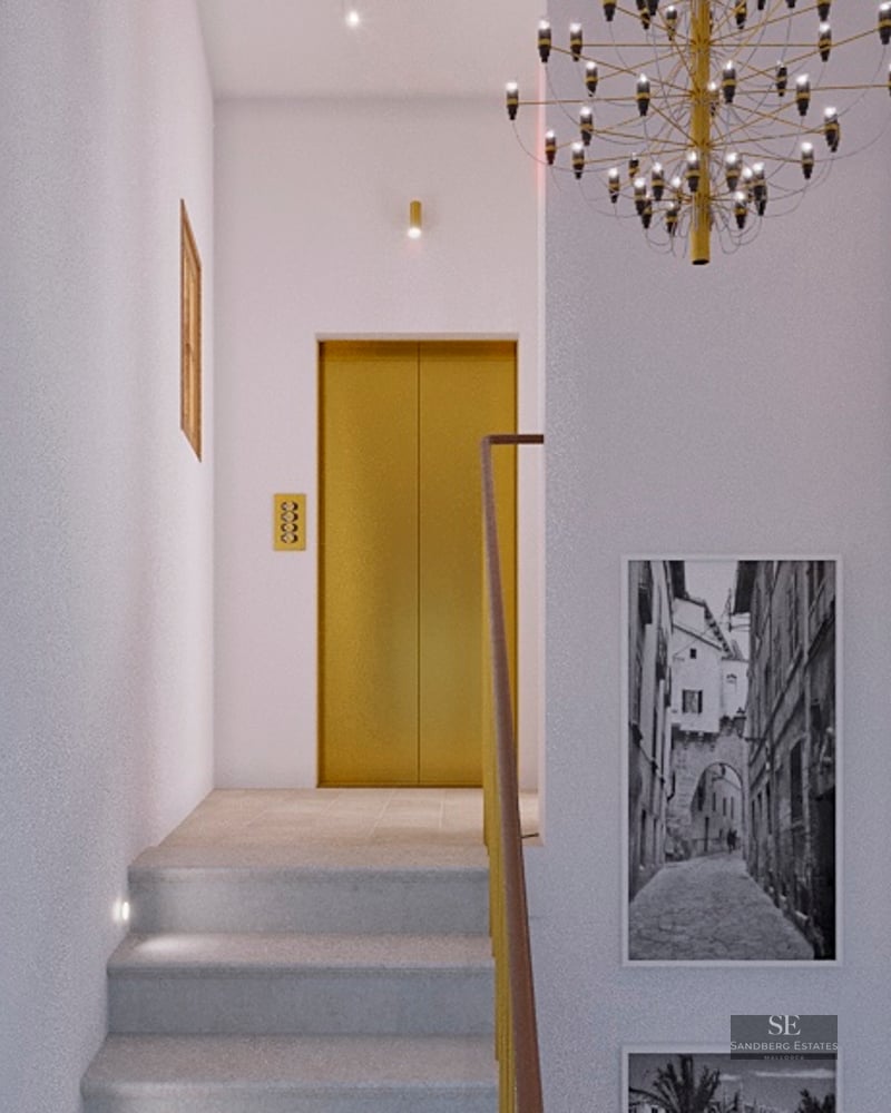 Modern hallway with stone stairs, a gold-finished elevator, black and white wall art, and a designer chandelier.