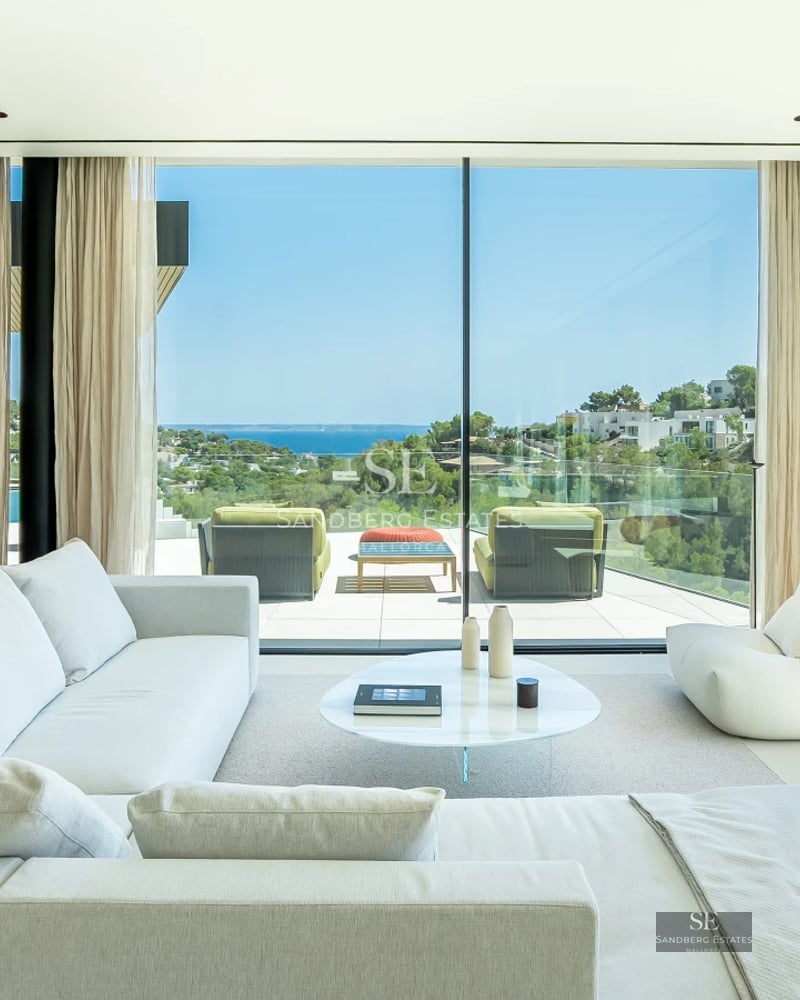 View of a modern villa with pool, large windows, covered terrace and elegant outdoor furniture. Lush garden.