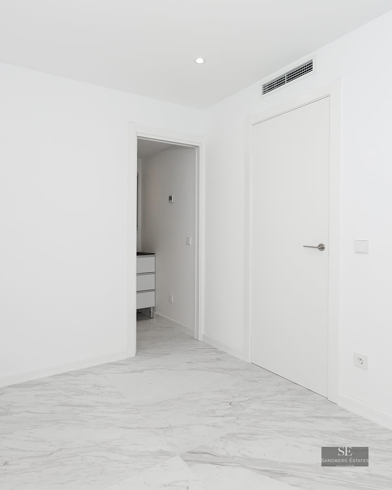 Bright empty room with white walls, polished grey-veined marble floors, and modern white doors.