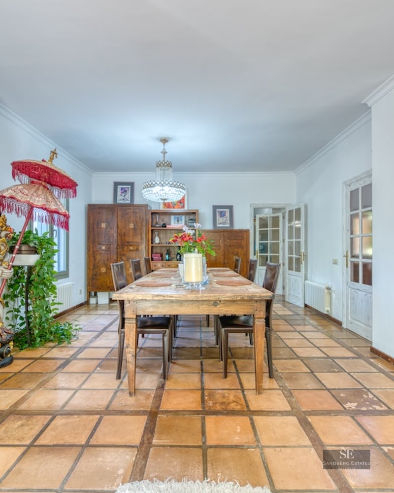 Spacious dining room featuring a wooden table, terracotta tile flooring, a fireplace, and an eclectic decorative statue.