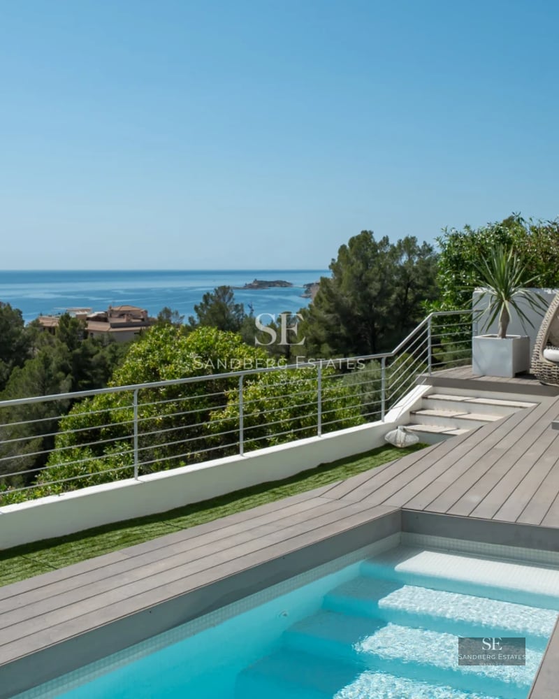 Modern exterior with reflective pool, manicured garden, and expansive glass windows. Minimalist and elegant design. Soft ambient lighting.