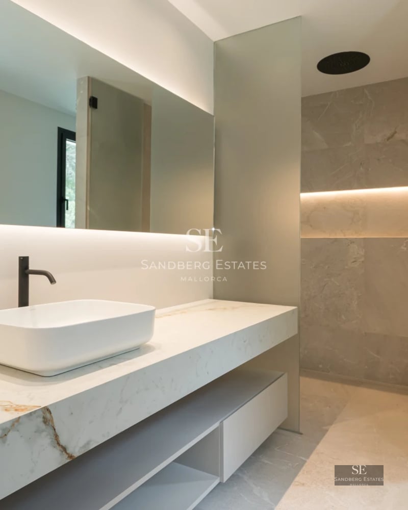 Image of an elegant pool with sun loungers and umbrellas, surrounded by gardens and with a modern building in the background.