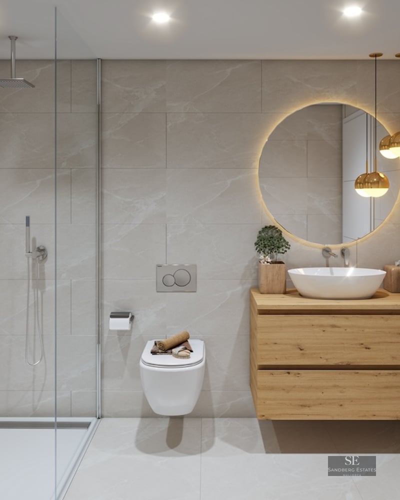 Contemporary bathroom featuring a glass walk-in shower, wooden vanity, round backlit mirror, and beige stone tiles.