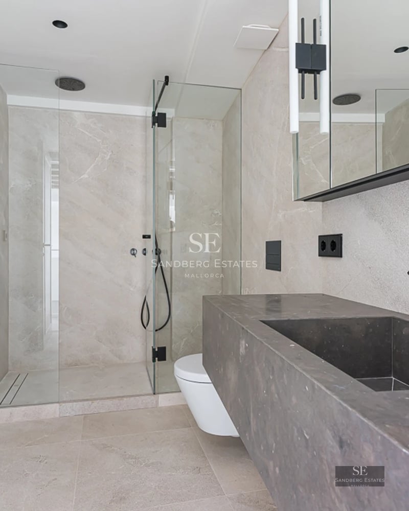 Spacious living room with floor-to-ceiling windows, fireplace, and garden view. Modern sofas and elegant decor. Abundant natural light.