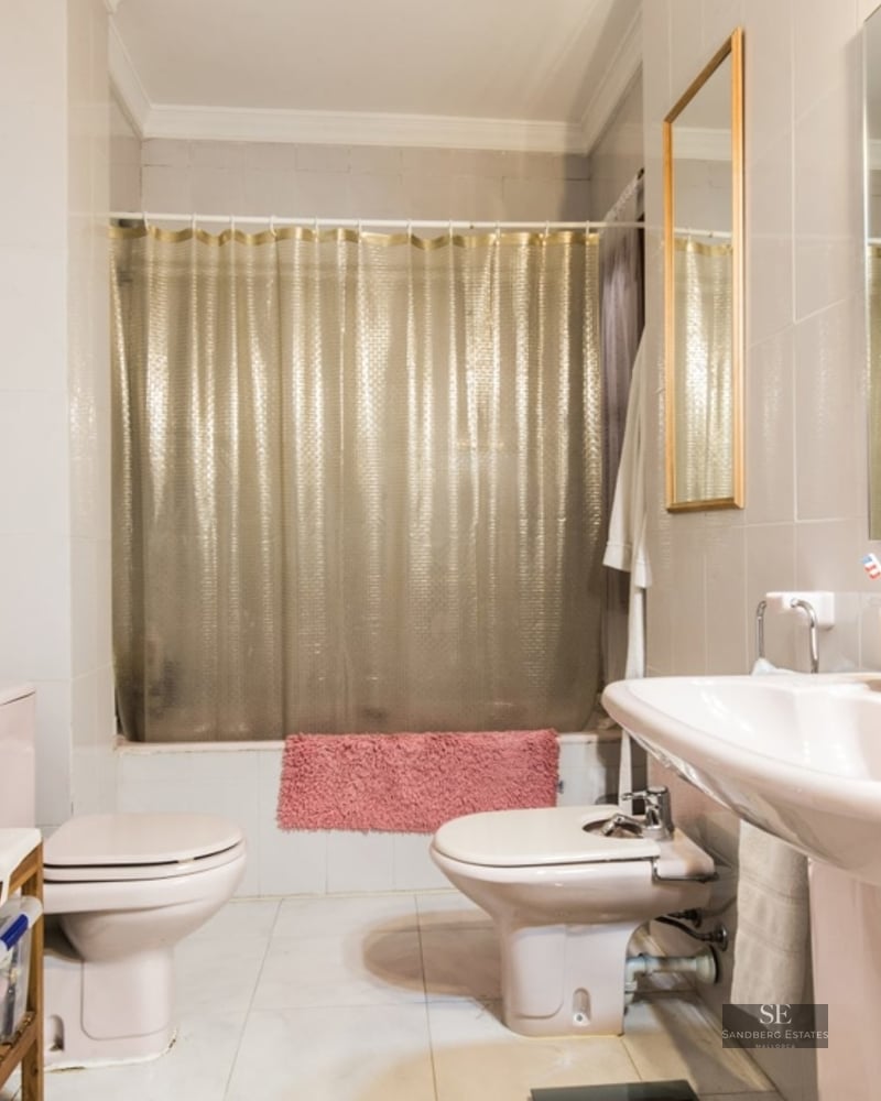 Bathroom with a double sink, toilet, bidet, and bathtub with a gold curtain.
