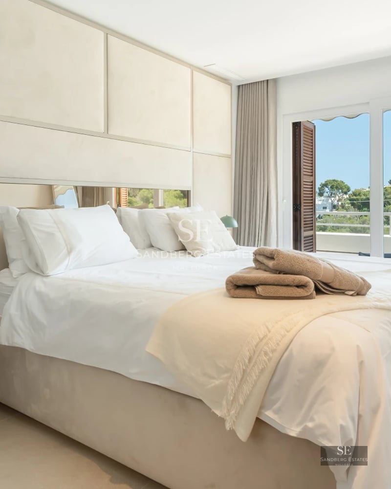 Aerial view of a luxurious villa with infinity pool, landscaped garden, and minimalist modern architecture. Clear blue sky.